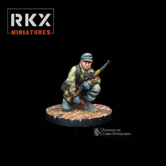 Figurine d'un tireur d'élite allemand (sniper) en position agenouillée avec fusil à lunette, camouflage automne, échelle 28mm, peinte par Chris Hindmarsh pour RKX Miniatures.