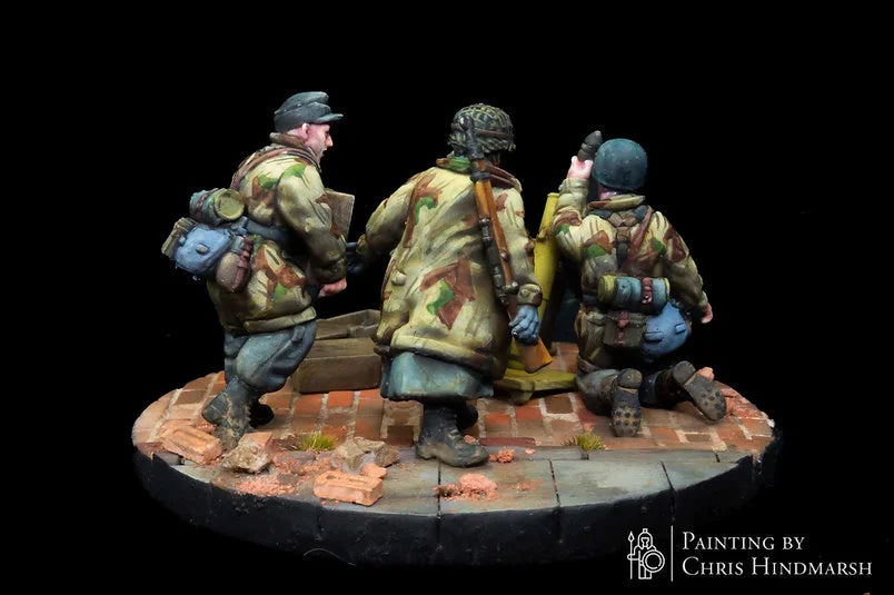 Servants de mortier Fallschirmjäger en position de tir, figurines d'infanterie spécialisée pour scénarios de combat Bolt Action, détails des caisses de munitions et du soclage urbain.