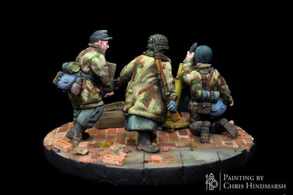 Servants de mortier Fallschirmjäger en position de tir, figurines d'infanterie spécialisée pour scénarios de combat Bolt Action, détails des caisses de munitions et du soclage urbain.